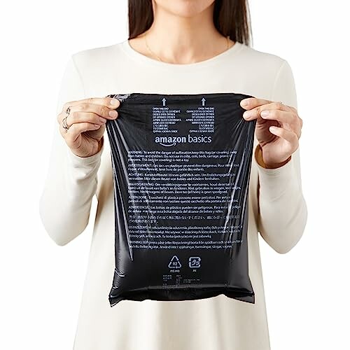 Person holding Amazon Basics paper shredder bag.