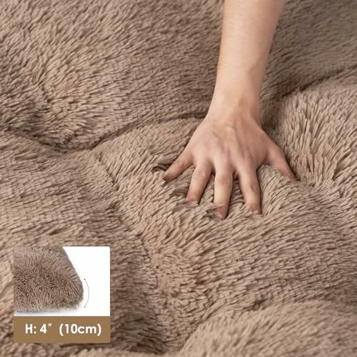 Hand pressing down on a fluffy, beige mattress showing its thickness.